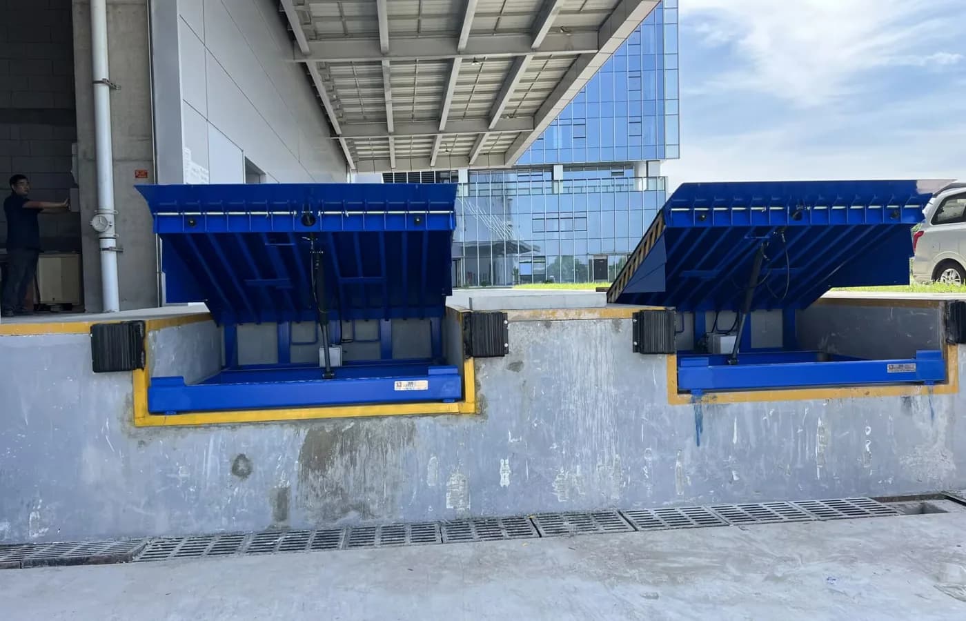 Two hydraulic dock levelers raised at a modern loading facility