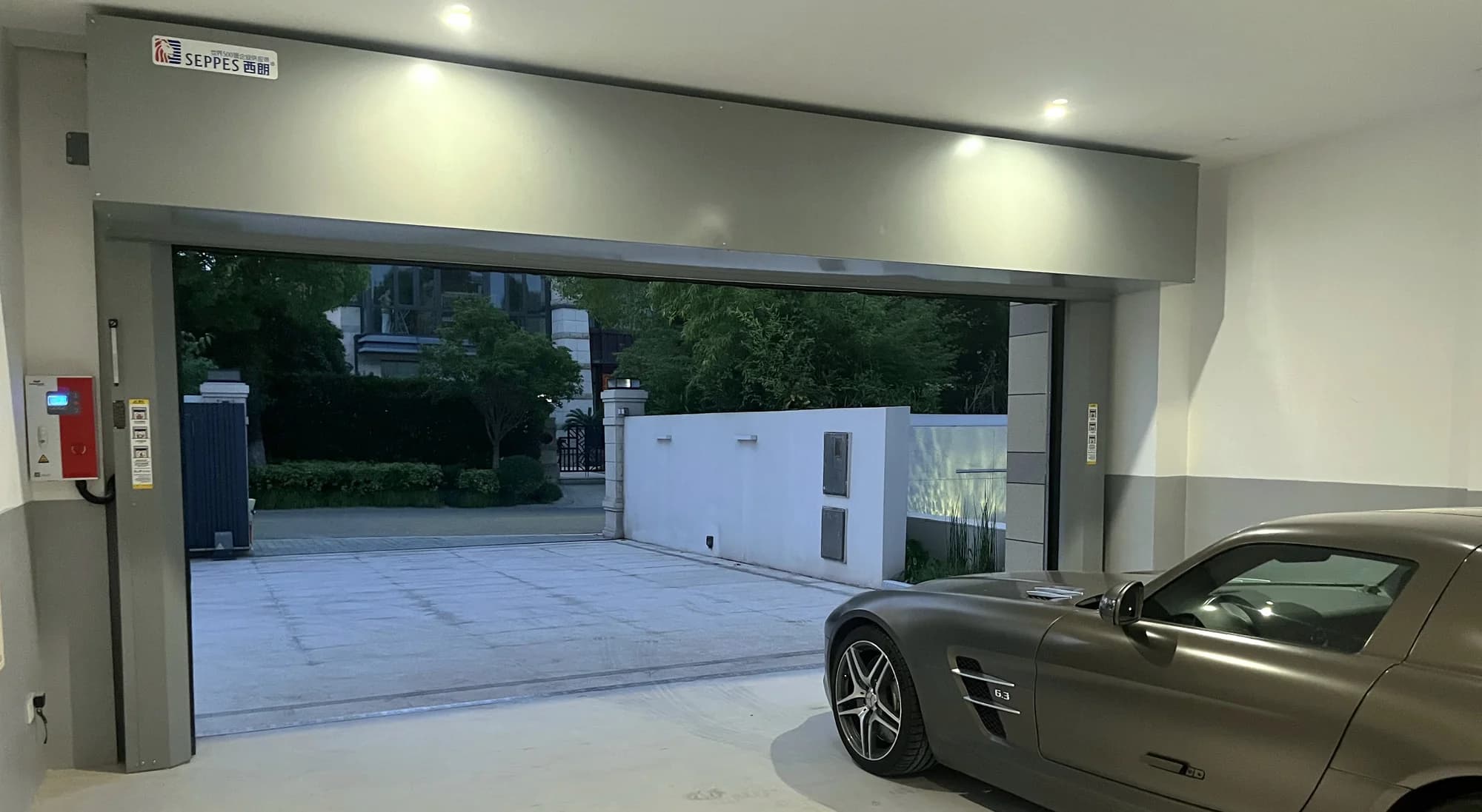 Dark rigid high-speed door installed at a private garage entrance
