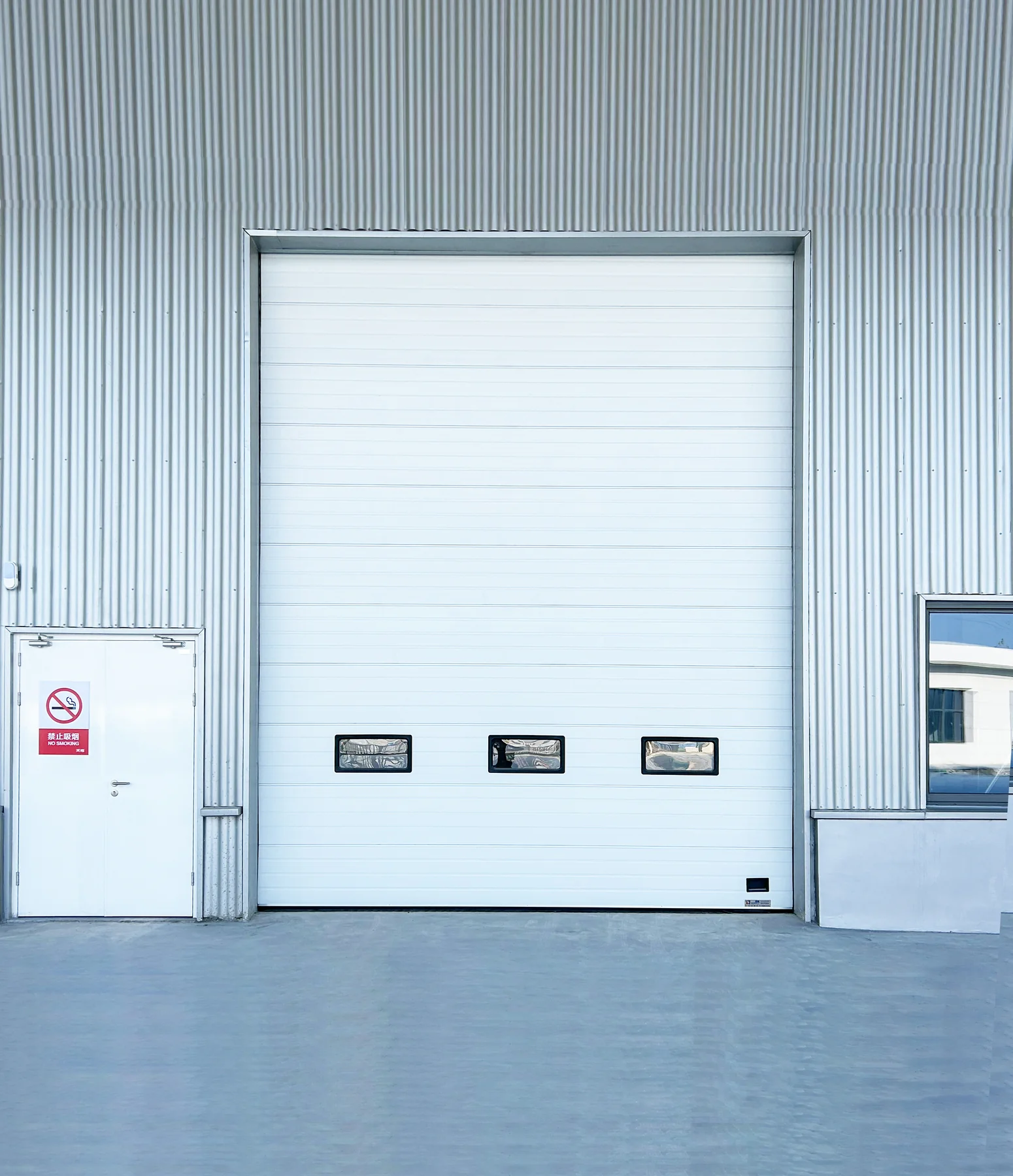 White SEPPES industrial sectional overhead door installed on a factory building